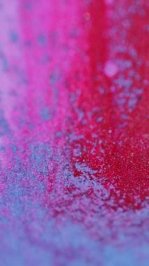 Dikey video. Parlak boya dokusu. Mürekkep akışı. Odaklanmamış parlak morumsu pembe renk tanecikleri sıvı damlalar dalga hareketi soyut sanat arkaplanı.