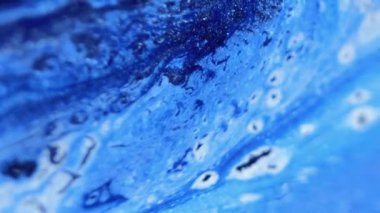 Boya dökülmüş. Parıldayan sıvı akışı. Bulanık mavi beyaz renk parıldayan parlak parçacıklar akrilik mürekkep dalgası soyut sanat arkaplanı dokusu.