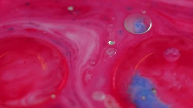 Köpüklü su. Mürekkep döküldü. Odaklanmamış pembe altın rengi yarı şeffaf damlalar yüzer güzellik emülsiyonu ışıldayan parçacıklar hareket eder soyut sanat arkaplanı.