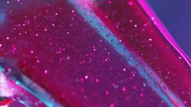 Yağlı sim. Parlayan sıvı. Pembe renkli jel hareketi kabarcıklar halinde şeffaf kristal mavi arkaplan soyut kopya alanı bulanıklığı.