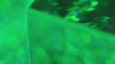 Renkli prizma. Gökkuşağı parlaması. Dönen şeffaf cam küp formu yeşil mavi pembe neon parıltı bokeh ışıklar soyut odaklanmış hareket.