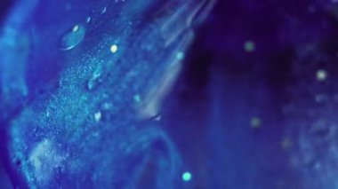 Damla mürekkebi. Parıltılı boya. Odaklanmamış mor renkte parıldayan parlak pırlanta şeffaf sıvı, soyut sanat arkaplanı var..