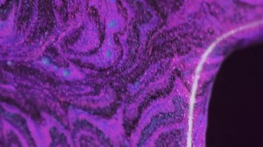 Islak sim dökülmüş. Boya damlası. Bulanık mor renkli parıldayan parlatıcı parçacıklar desen sıvı mürekkep akışı soyut sanat arkaplanı.