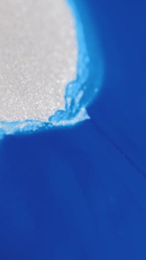 Dikey video. Boya dökülmüş. Parıldayan sıvı dalga. Odaklanmamış mavi beyaz renk parlaklığı parlaklığı mürekkep emülsiyonu hareket soyut sanat arkaplanı.