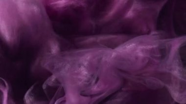 Köpüklü boya suyu. Buhar bulutu. Odaklanmamış mor renkte parıldayan parçacıklar koyu siyah soyut sanat arka planında süzülen duman dokusu.