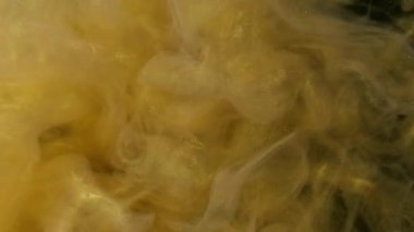 Işıldayan mürekkep suyu. Yüzen buhar. Bulanık sarı altın rengi, parlak parçacıklar, siyah soyut sanat arka planında sis dalgası hareketi..