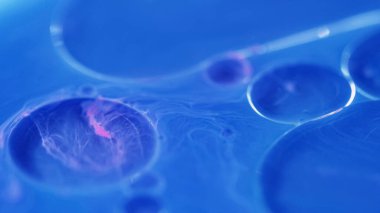 Serum damlası. Köpüklü sıvı. Odaklanmamış mavi pembe renk şeffaf yuvarlak yağ kabarcıkları yüzen sis dokusu boya su akışı soyut sanat arka planı.