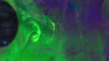 Mürekkep arkaplanı. Boya girdapları. Fantezi sıvısı. Yeşil mavi ışıldayan parçacıklar ıslak pigment soyut karışım hipnotik sızıntı şeffaf suda yayılıyor.