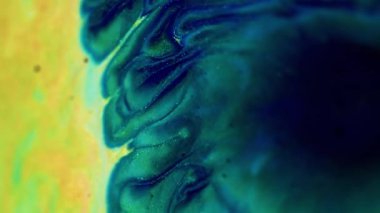 Parlak mürekkep sıçraması. Köpüklü sıvı dalgası. Odaklanmamış mavi indigo yeşil renk altın rengi parlak pullu partiküller sıvı boya emülsiyon su akışı hareket soyut sanat arka planı.