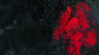 Parıldayan sıvı akışı. Boya sıçraması. Sıcak volkanik lav. Bulanık kırmızı, parlak parçacıklar akrilik mürekkep emülsiyonu koyu soyut sanat arkaplanını karıştırır.