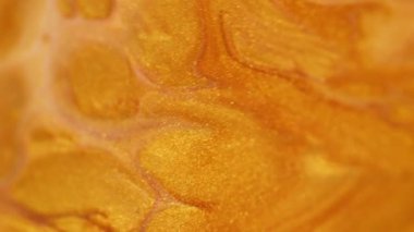 Parıldayan sıvı akışı. Akrilik boya dökülmüş. Parlak doku. Odaklanmamış altın sarısı renk parıldayan pullu parçacıklar pigment sıvı dalga hareketi soyut sanat arkaplanı.