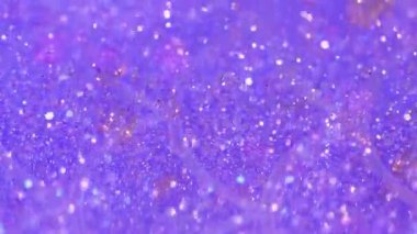 Sıvı pırıltısı. Parıldayan sıvı akışı. Odaklanmamış mor renkli ışıl ışıl pullu parçacıklar şeffaf boya emülsiyonunda titreşiyor. Bokeh ışıklarıyla soyut sanat arkaplanı..