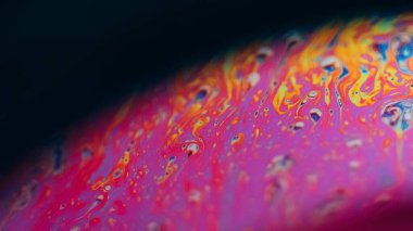 Mürekkep rengi gökkuşağı. Psikedelik spektrum. Odaklanmamış pembe mavi renk eğrisi koyu siyah soyut sanat arka planında yağ kimyasal sıvı akışı.