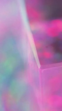 Dikey video. Odaklanmış küp. Renkli bokeh. Dönen cam prizması neon pembe daireler parıldayan mor aydınlatma soyut arkaplan hareketini yansıtır.