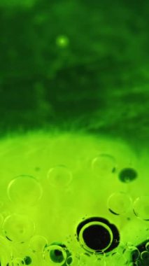 Dikey video. Yağlı boya balonları. Renk sisi. Mürekkep suyu. Asit sıvısı. Odaklanmamış yeşil boya jeli damlacıkları yüzen hareket duman dokusu koyu siyah soyut sanat arka planı.