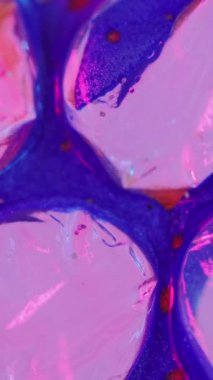 Dikey video. Boya baloncukları. Parlak sıvı damlası. Odaklanmamış floresan pembe kırmızı renk parlak yağ lekesi su sızıntısı mozaik hücre yapısı soyut sanat arka planı.