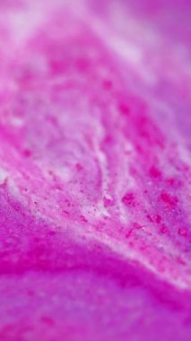 Dikey video. Parıldayan sıvı dökülmüş. Boya karışımı. Odaklanmamış morumsu pembe beyaz renkli ışıl ışıl parçacıklar sıvı mürekkep akışı kademeli hareket soyut sanat arkaplanı.