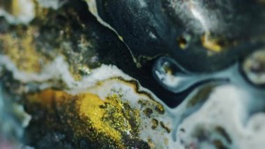 Dikey video. Mürekkep döküldü. Parlak sıvı karışımı. Odaklanmamış siyah beyaz sarı renk parıldayan ıslak boya akışı bokeh hafif mermer dokusu soyut sanat arkaplan.