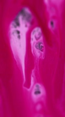 Dikey video. Boya damlası. Renkli dökülme. Etkisiz hale getirilmiş pembe pembe pigment simli mürekkep harmanı sanatın soyut arka planını yayıyor..