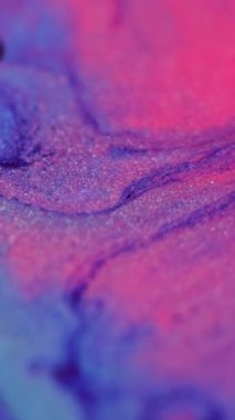 Dikey video. Parıldayan sıvı. Mürekkep akışı. Mermer dokusu. Odaklanmamış neon mavisi, pembe, parlak, ışıldayan parçacıklar boya karışımı, dökülme hareketi, soyut sanat arkaplanı..