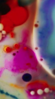 Dikey video. Boya baloncukları. Mürekkep kaleydoskop. Beyaz süt dokusu soyut sanat arka planında odaksız mavi kırmızı renk akrilik boya sıvı su akışı simetrik tasarım.