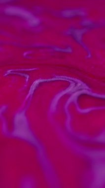 Dikey video. Parlak mürekkep karışımı. Titreyen girdap. Odaklanamayan parlak neon pembe renk parçacıkları desen boyası su girdabı hareket sanatı soyut arkaplan.
