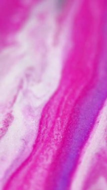 Dikey video. Parlak sıvı damlası. Mürekkep döküldü. Pembe, parlak, beyaz, metalik desenli, parlak, dalgalı, göz alıcı, soyut sanat arkaplanı..