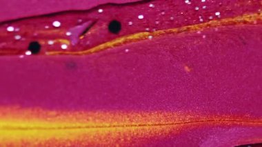 Dikey video. Boya damlası. Parıldayan jel sıvısı. Odaklanmamış parlak morumsu pembe sarı renk parıldayan pullu parçacıklar desen mürekkep akışı soyut sanat arka planı..