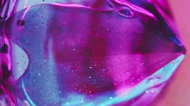 Dikey video. Neon değerli taş. Parlak sıvı damlası. Odaklanmamış floresan açık pembe renk şeffaf parlak parçacıklar jel boya dökülmesi kristal prizma soyut sanat arka planı.