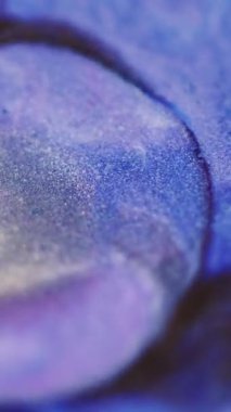 Dikey video. Boya damlası. Parlak mürekkep sıçraması. Odaklanmamış mavi mor renkli parıldayan desen sıvı parlatıcı kabarcık açıcı hareket soyut sanat arkaplanı.