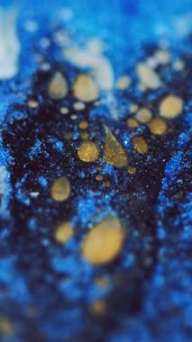 Dikey video. Parlak boya akışı. Parlayan yağ damlaları. Odaklanmamış mavi altın rengi parıldayan desen mürekkep dalgası hareketi soyut sanat arkaplanı.