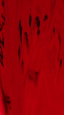 Dikey video. Mürekkep damlası. Boya dökülmüş. Odaklanmamış kırmızı renk, ıslak parlaklık, sıvı karışımı yeşil beyaz bokeh ışıklı cam, soyut sanat arka planında hareket.