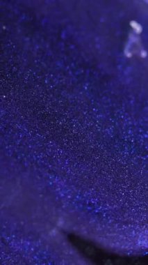 Dikey video. Işıldayan doku. Islak sim akışı. Odaklanmamış mavi menekşe rengi parıltılı boya dalgası hafif cazibeli soyut sanat arkaplanı bokeh.