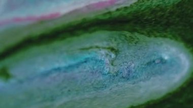 Dikey video. Islak sim damlası. Boya dökülmüş. Odaklanmamış yeşil pembe renk parıldayan parçacıklar desen karışık akış hareketi soyut sanat arkaplanı.