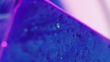 Köpük dokusu. Donmuş boya. Odaklanmamış mavi pembe neon yüzler geometrik şekil ıslak yüzey soğuk küp hareket soyut sanat arka planı üzerinde parıldayan parlak sıvı.