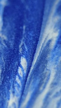 Dikey video. Parlak mürekkep damlası. Akrilik dökülmesi. Odaklanmamış mavi beyaz renkli parlak desenli boyalı parlatıcı harmanlanmış hareketli dekoratif soyut sanat arka planı.