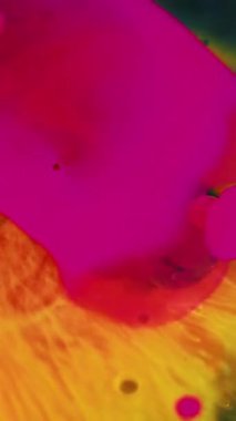 Dikey video. Boya sıçraması. Yağ damlası. Renk sisi. Odaklanmamış pembe turuncu mürekkep karışımı su kabarcıkları siyah soyut sanat arka planında akış hareketi.