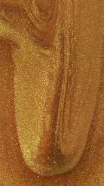 Dikey video. Islak sim damlası. Işıldayan doku. Odaklanmamış altın rengi ışıl ışıl boya akışı hareket lüks soyut sanat arka planını ortaya çıkarıyor..