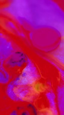 Dikey video. Su damlasını boya. Parlak sıvı kabarcıkları. Odaklanmamış parlak neon kırmızı mor renkli parıldayan desen yağlı mürekkep karışık hareket soyut sanat arka planı.