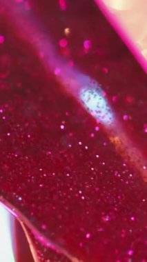 Dikey video. Sıvı sim. Hareketli pırıltılar. Pembe parlak parlak parlak altın bokeh kirişleri cam rengi jel dokusunda bulanık arka plan gökkuşağı ışıkları.