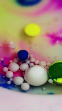 Dikey video. Boya baloncukları. Renkli yağ sıvısı. Odaklanmamış mor mavi akrilik mürekkep boyası su karışımı beyaz süt dokusunda yüzen damlacıklar soyut sanat arka planı.