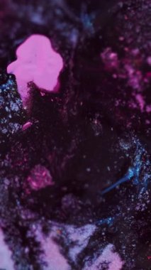 Dikey video. Parıldayan sıvı dökülmüş. Neon boya damlası. Bulanık floresan pembe mavi siyah renk ışıl ışıl parçacıklar desen karışım mürekkep dalga hareketi karanlık soyut sanat arkaplan.