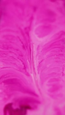 Dikey video. Pigment girdapları. Boya akışı. Odaklanamayan parlak göz kamaştırıcı mor pembe beyaz renkli mürekkep sıvısı karışımı akışı sanatın soyut arka planını yayıyor..