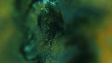 Dikey video. Bulanık mermer dokusu. Parıltılı boya akışı. Odaklanmamış yeşil altın sarısı siyah renk parıldayan mürekkep karışımı hareket soyut sanat arkaplanı.