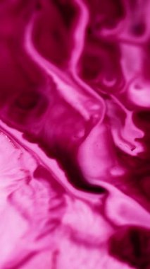 Dikey video. Boya suyu akışı. Alkol mürekkebi dökülmüş. Bulanık pembe beyaz renk parıldayan toz parçacıkları sıvı pigment emülsiyon sızıntısı karışık hareket soyut sanat arkaplanı.