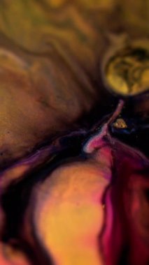 Dikey video. Boya akışı. Parlak sıvı dokusu. Odaklanmamış siyah pembe turuncu turuncu altın rengi parlak toz parçacıkları mürekkep sızıntısı emülsiyon harmanlanmış hareket soyut sanat arkaplanı.