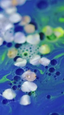 Dikey video. Çiçek özü. Jel sıvısı. Odaklanmamış mavi beyaz neon rengi doğal çiçek deseni yağ kabarcığı soyut arkaplan.