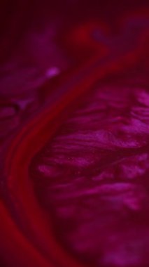 Dikey video. Parıltılı boya akışı. Köpüklü sıvı. Odaklanmamış pembe kırmızı parlatıcı sıvı parıldayan toz parçacıkları desen mürekkep dökülmesi pigment karışık hareket soyut sanat arka planı.