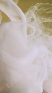 Dikey video. Mürekkep suyu girdabı. Yaratıcı duman. Fış sanatı. Beyaz buhar bulutu ipek sıvı boya dokusu bulanık sarı altın parçacıkları renk soyut arkaplan.