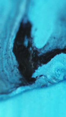 Dikey video. Sıvı boya akışı. Parlak mürekkep karışımı. Odaklanmamış mavi renk damlası hareketi ıslak ışıldayan jel yağ emülsiyon parçacıkları sanat soyut arkaplan.
